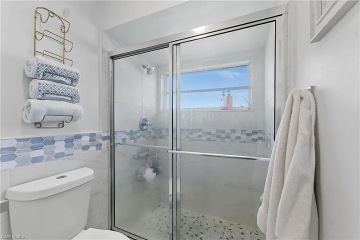 Full bath with a shower stall and tile walls