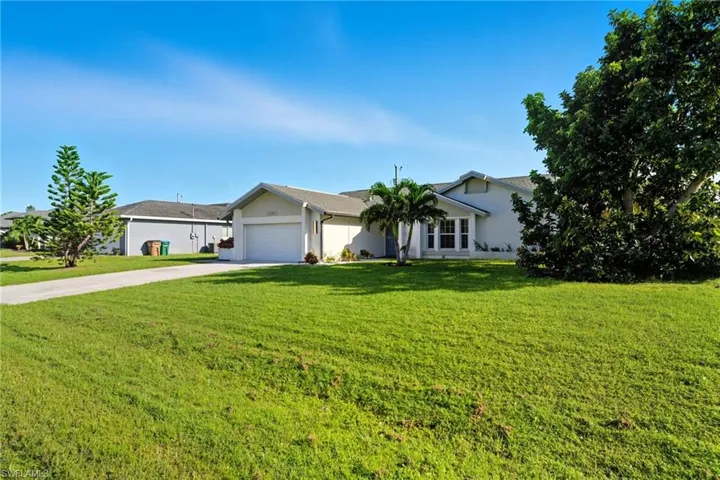 Ranch-style house featuring driveway, stucco siding, a front yard, and a garage