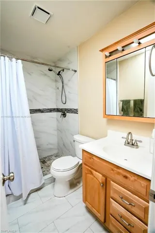 Bathroom featuring vanity, a stall shower, and light marble finish flooring