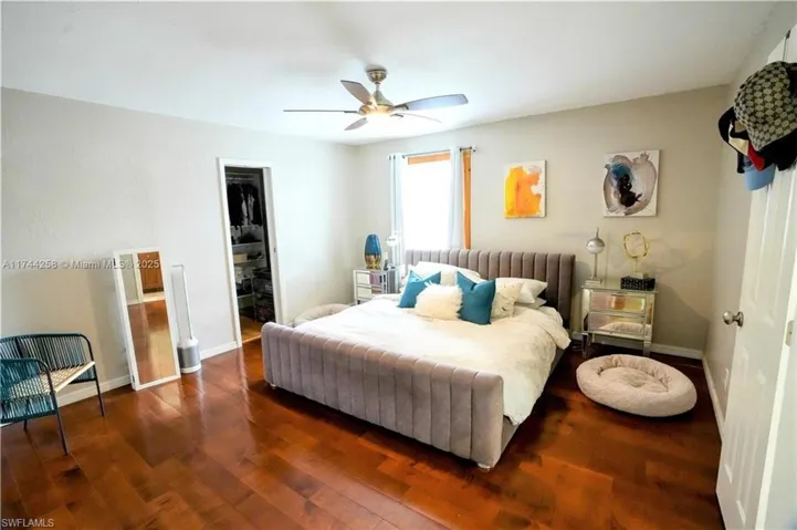 Bedroom with wood finished floors, a walk in closet, and a ceiling fan