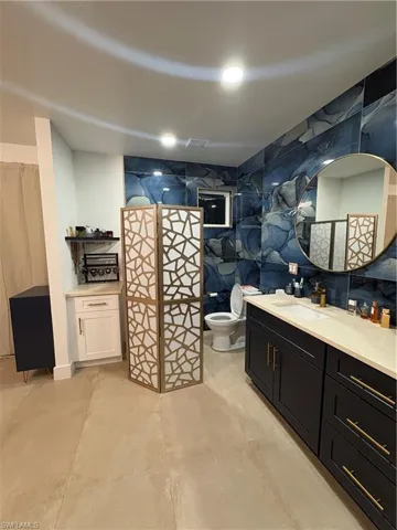 Bathroom featuring tile walls, vanity, toilet, and walk in shower