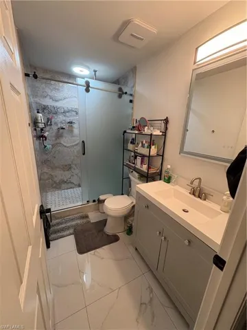 Bathroom with vanity, a shower with shower door, and toilet