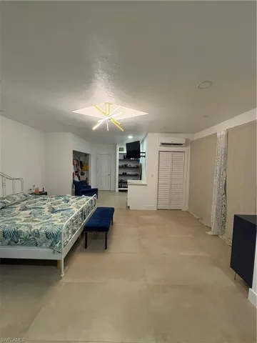 Bedroom featuring a wall mounted air conditioner and an inviting chandelier