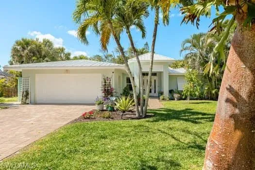 View of front of property with a front lawn, a garage, driveway, and stucco siding