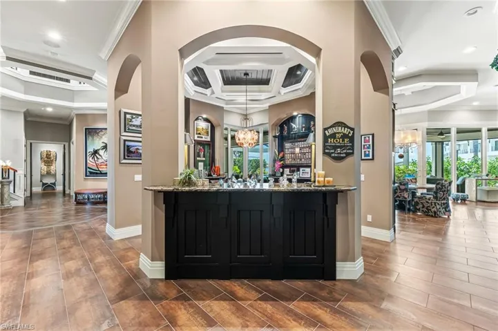 Community bar area featuring crown molding, a chandelier, arched walkways, recessed lighting, and coffered ceiling