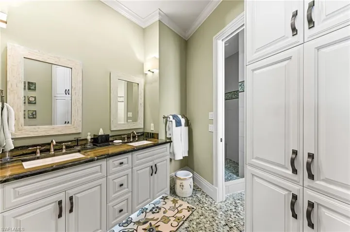 Guest Bathroom with double vanity, ornamental molding, tiled shower, bathtub, additional cabinetry