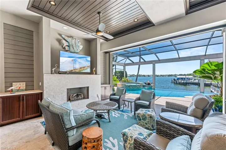View of lanai, featuring an outdoor living space with a fireplace, a pool with connected hot tub, ceiling fan, and screened enclosure