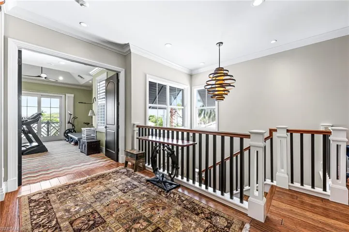Hall with an upstairs landing, recessed lighting, ornamental molding, and a chandelier over stairway