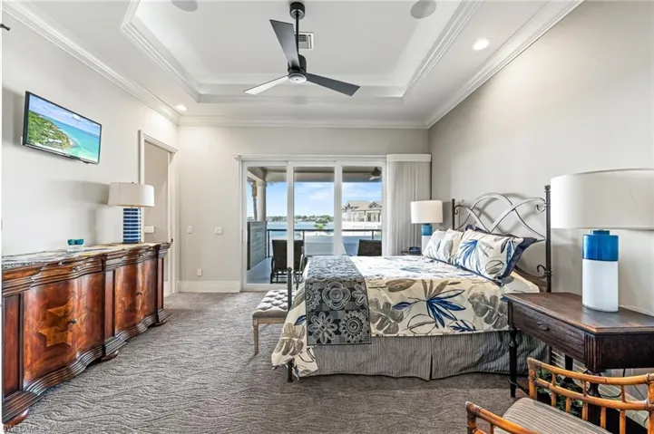 Guest Bedroom with access to outside 2nd floor lanai, a tray ceiling, carpet flooring, crown molding, and recessed lighting