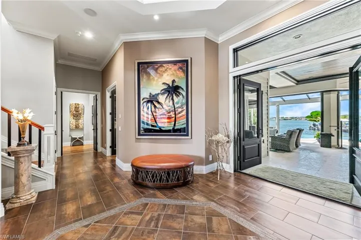 Entrance foyer featuring recessed lighting, a water view, crown molding, tiled floors, and stairway