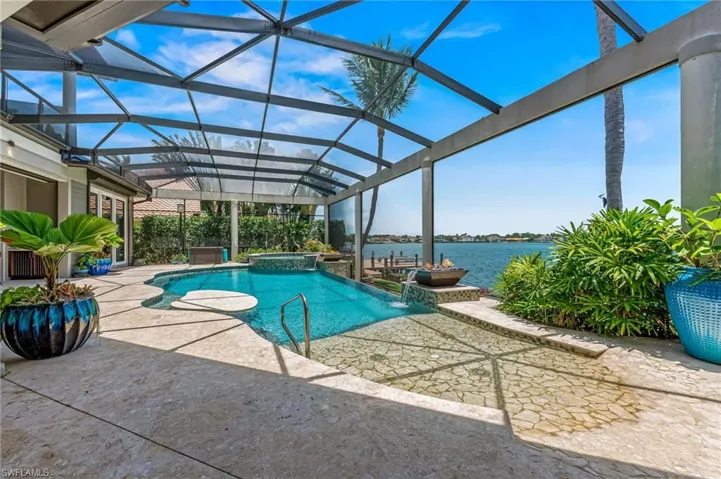 View of pool connected to hot tub, a water view, and a lanai