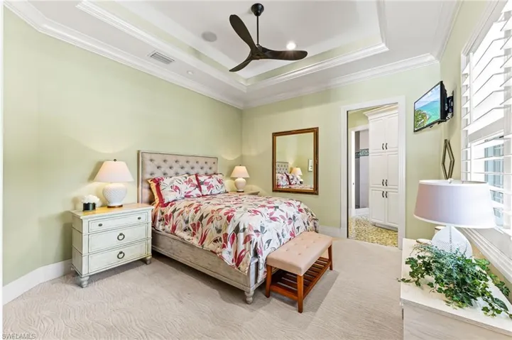 Guest Bedroom with crown molding, a raised ceiling, a ceiling fan, and light carpet