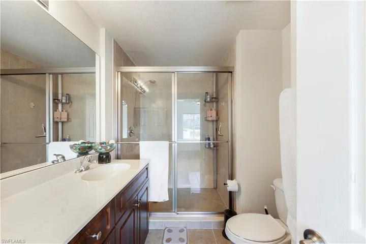 Full bathroom with vanity, a stall shower, light tile patterned floors, and a textured ceiling