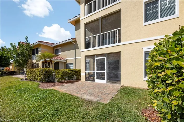 Rear view of property with a sunroom, stucco siding, a tiled roof, a yard, and a patio area
