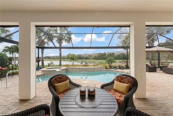 View of pool with outdoor dining area, a patio area, a sunroom, a pool with connected hot tub, and screened-in enclosure