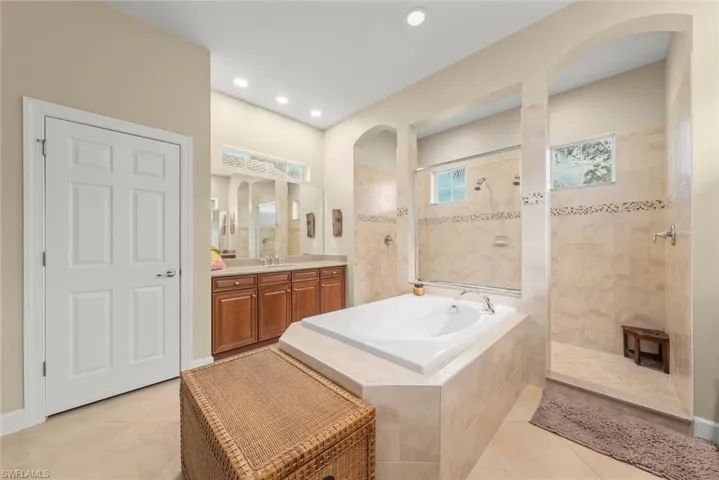 Full bathroom with vanity, light tile patterned flooring, a walk in shower, a bath, and recessed lighting