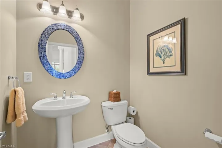 Half bathroom featuring toilet, sink, and tile patterned floors