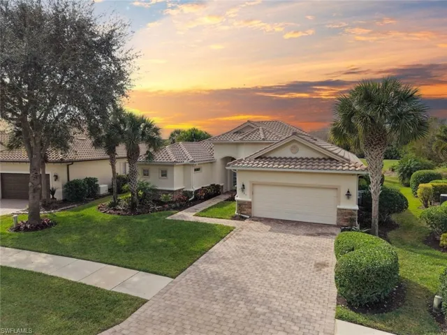 Single Family house with a tiled roof, a lawn, stucco siding, brick paver driveway, and a two-car garage