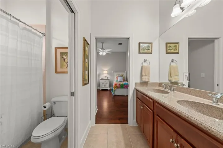 Bathroom with double vanity, a shower and tub with shower curtain, and light tile patterned flooring