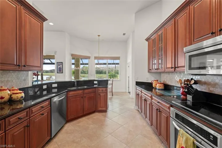 Kitchen with backsplash, a peninsula, stainless steel appliances, granite countertops, and recessed lighting