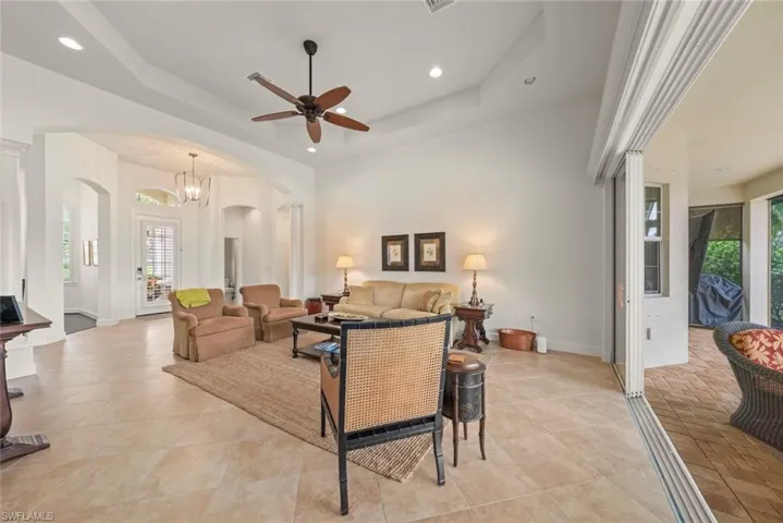 Living area featuring a chandelier, a raised ceiling, recessed lighting, and a ceiling fan