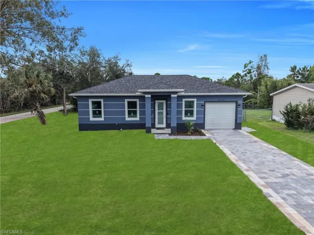 Blue exterior siding with white trim, a dark shingle roof, a paver driveway, and a single-car garage