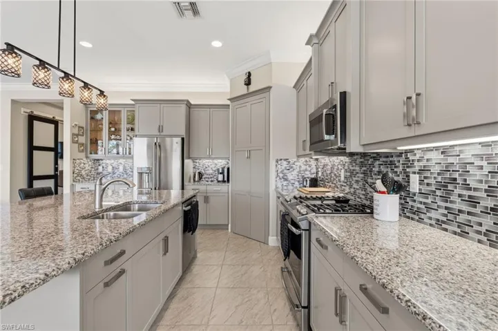 Elegant kitchen accents, stainless steel appliances, glass tile backsplash.