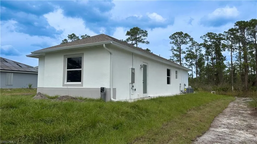 View of home's exterior featuring stucco siding, central air condition unit, and a yard