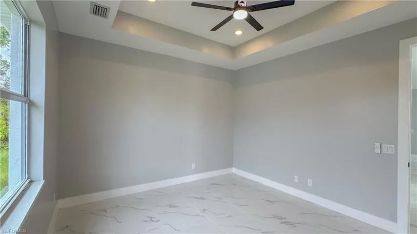 Unfurnished room featuring marble finish floor, baseboards, and a healthy amount of sunlight