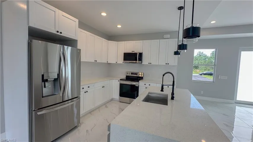 Kitchen with marble finish floor, a sink, appliances with stainless steel finishes, and recessed lighting