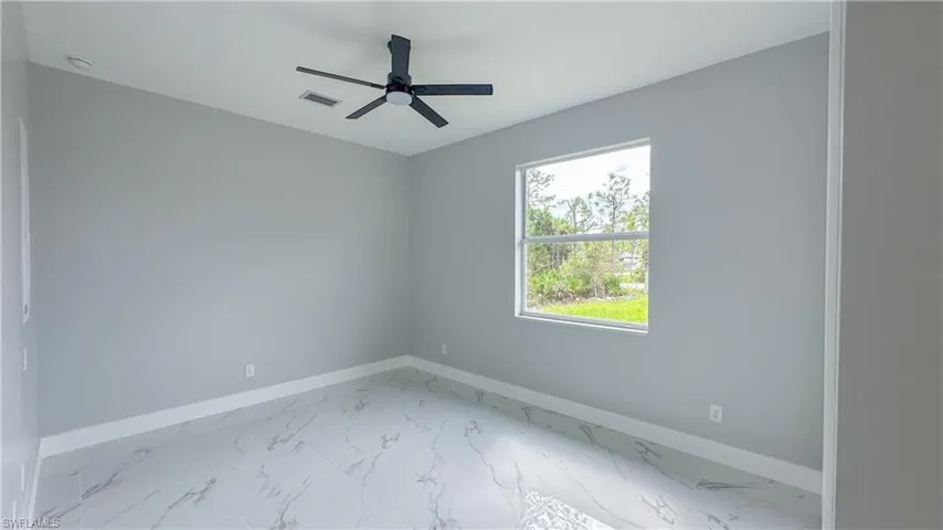 Unfurnished room featuring a ceiling fan, marble finish floor, baseboards, and visible vents