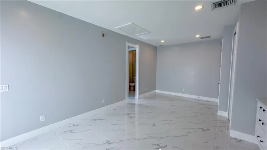 Spare room featuring marble finish floor, baseboards, and visible vents