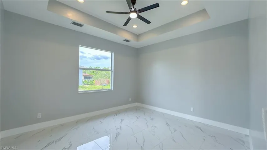 Spare room featuring a ceiling fan, a tray ceiling, baseboards, and recessed lighting