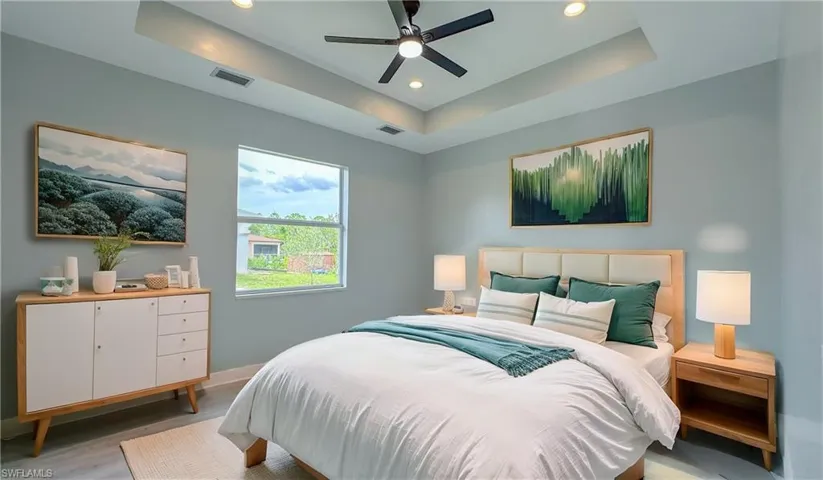 Bedroom featuring recessed lighting, visible vents, light wood-style floors, and a raised ceiling