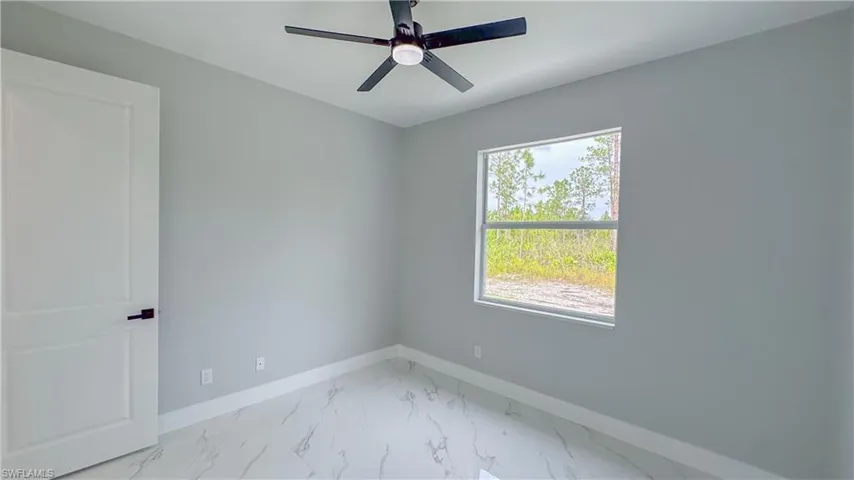 Spare room featuring baseboards, marble finish floor, a ceiling fan, and plenty of natural light