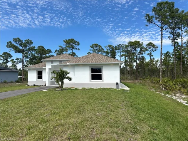 View of front of property featuring a front lawn, driveway, and stucco siding