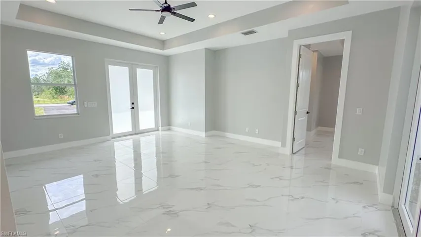Empty room with a tray ceiling, french doors, marble finish floor, baseboards, and visible vents