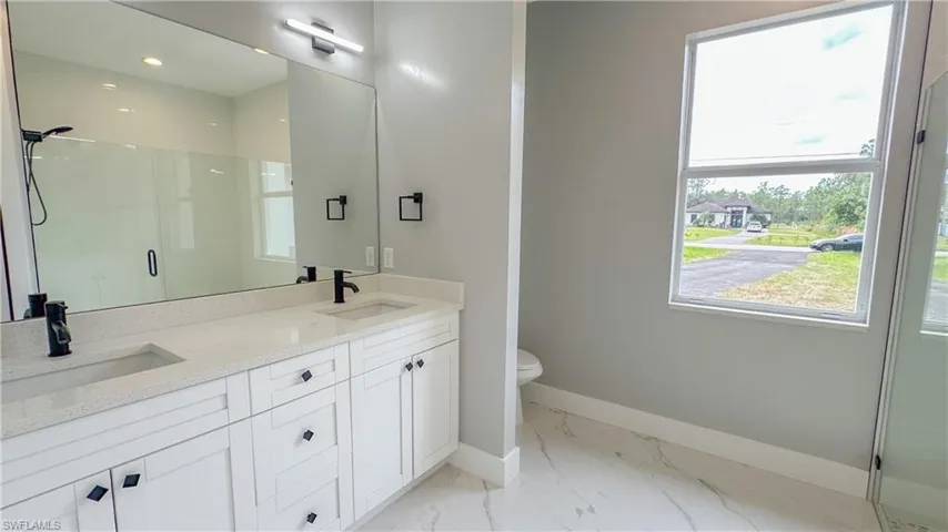 Bathroom featuring baseboards, marble finish floor, a sink, and a shower stall