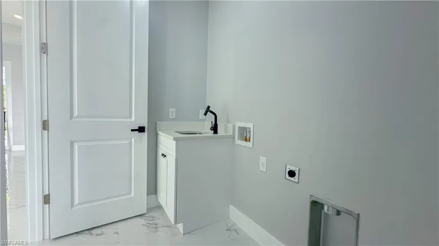 Laundry room with washer hookup, marble finish floor, a sink, electric dryer hookup, and cabinet space