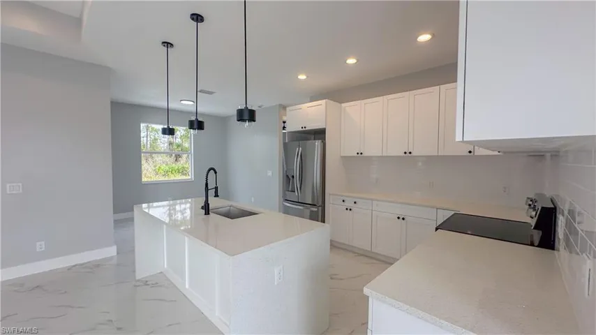 Kitchen featuring marble finish floor, stainless steel fridge with ice dispenser, range, and a sink