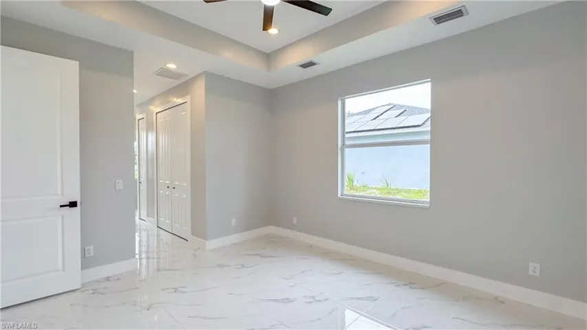 Spare room with marble finish floor, baseboards, ceiling fan, and visible vents