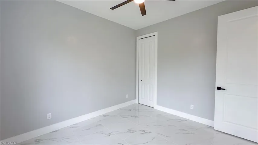 Unfurnished room featuring marble finish floor, baseboards, and ceiling fan