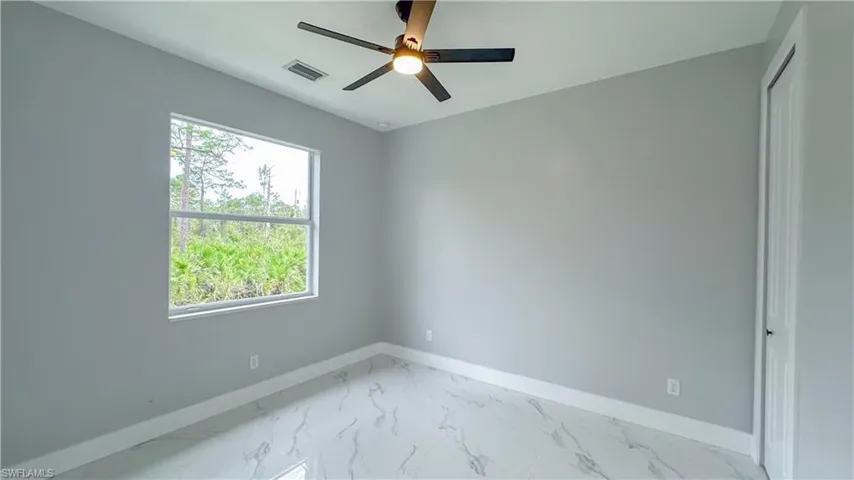 Unfurnished room with marble finish floor, baseboards, visible vents, and a ceiling fan