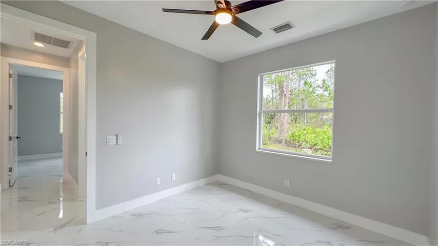 Empty room with baseboards, visible vents, and ceiling fan