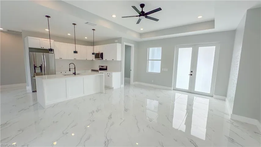 Kitchen with a tray ceiling, baseboards, a sink, visible vents, and appliances with stainless steel finishes