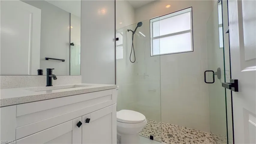 Bathroom featuring toilet, a stall shower, and vanity