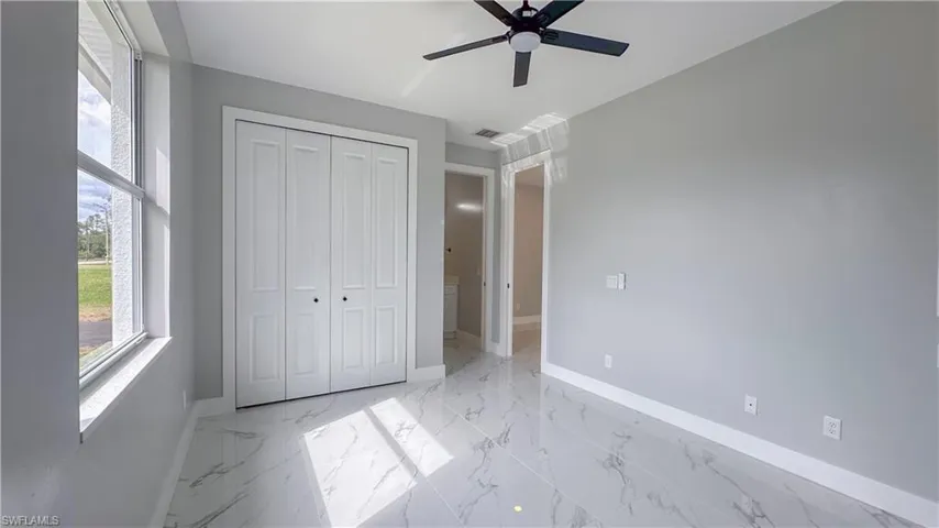 Unfurnished bedroom featuring baseboards, marble finish floor, visible vents, a ceiling fan, and a closet