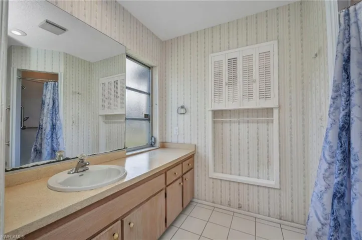 Full bath with vanity, tile patterned floors, a shower with curtain, and wallpapered walls