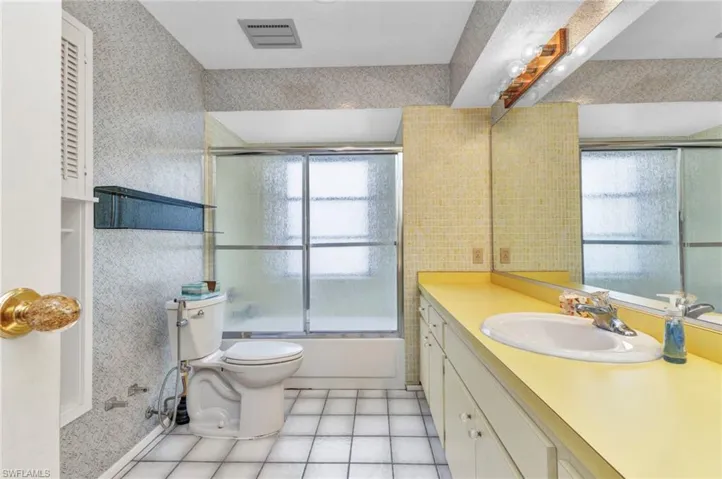 Full bath with healthy amount of natural light, vanity, toilet, and tile patterned floors