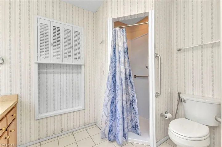 Full bath with toilet, a stall shower, tile patterned floors, and vanity